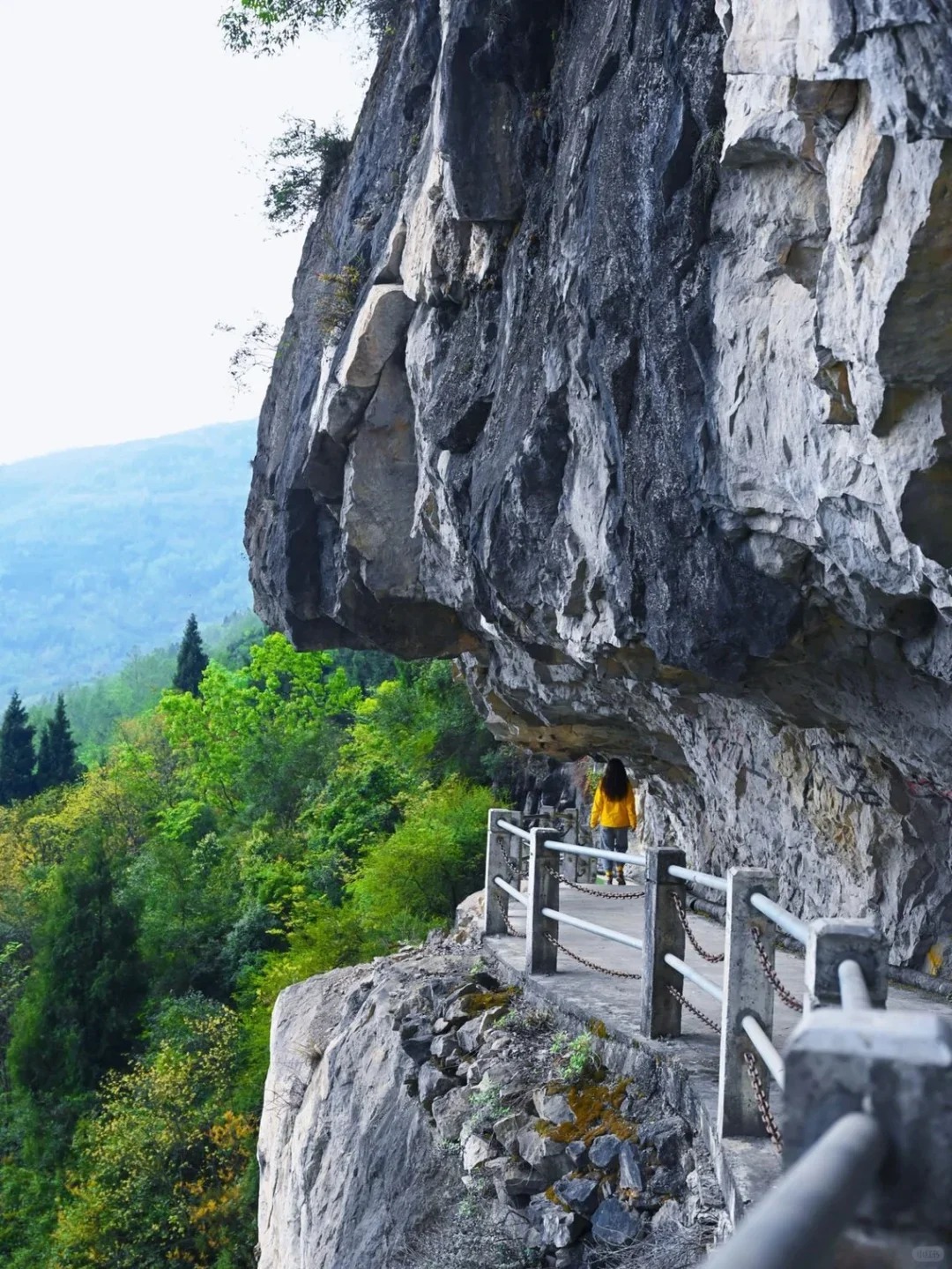 Woman walking along a cliffside trail on Chengdu’s Qianyuan Mountain with beautiful scenery